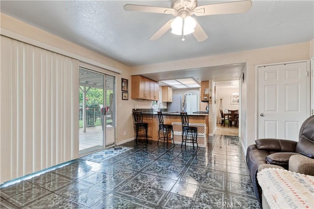 living area featuring a ceiling fan and baseboards