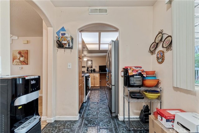 hall featuring arched walkways and baseboards