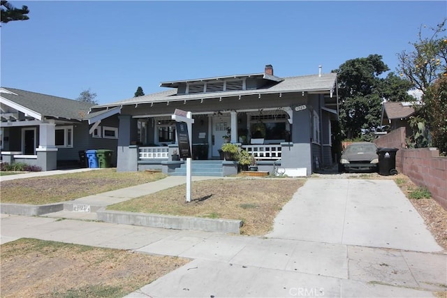 bungalow featuring fence, covered porch, and a chimney