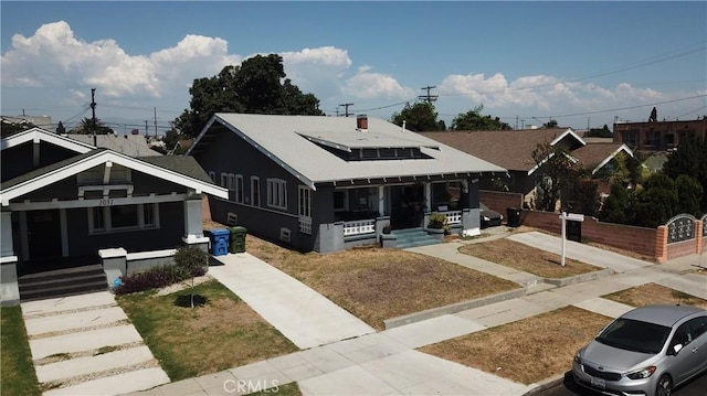 bungalow-style home featuring a porch, concrete driveway, solar panels, and a shingled roof