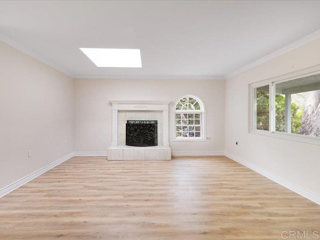 unfurnished living room with a skylight, baseboards, ornamental molding, and light wood finished floors