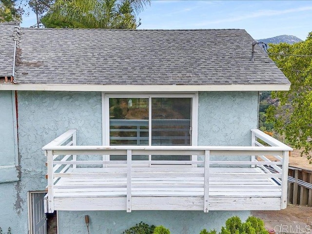 exterior space with a shingled roof and stucco siding