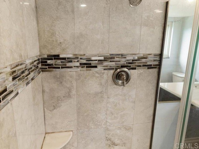 room details featuring toilet and tiled shower