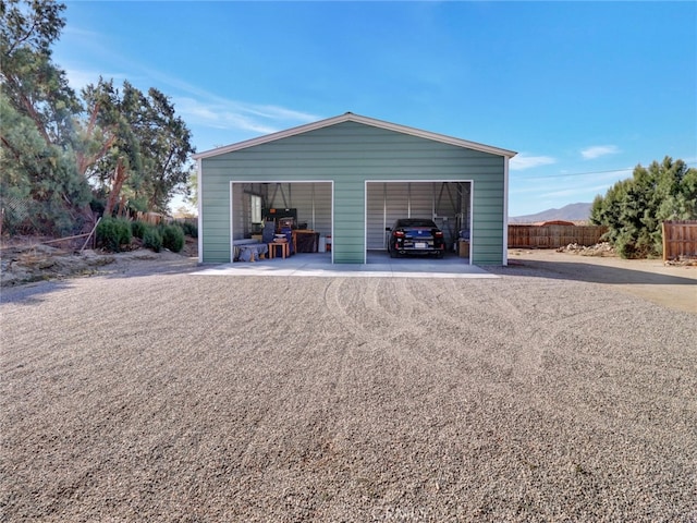 detached garage with dirt driveway and fence