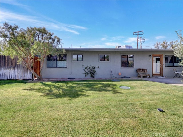 back of property featuring a yard, a patio area, stucco siding, and fence