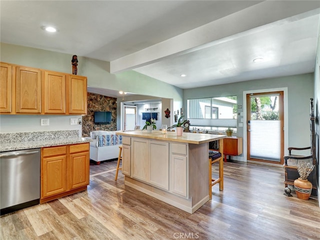 kitchen featuring a breakfast bar, stainless steel dishwasher, open floor plan, and light wood-type flooring