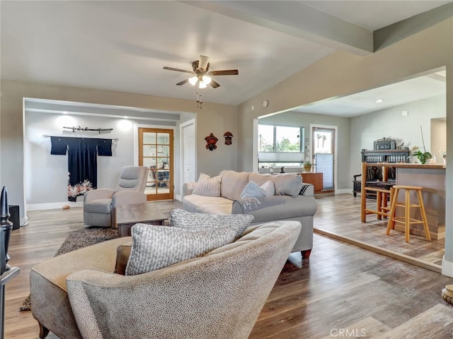 living room with a ceiling fan, baseboards, and wood finished floors