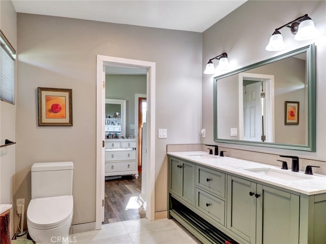 bathroom with a sink, double vanity, toilet, and tile patterned flooring