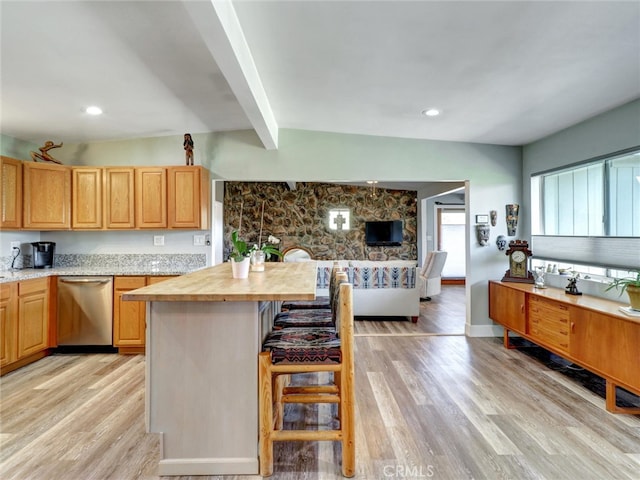 kitchen with wood counters, a breakfast bar, light wood-type flooring, a center island, and stainless steel dishwasher
