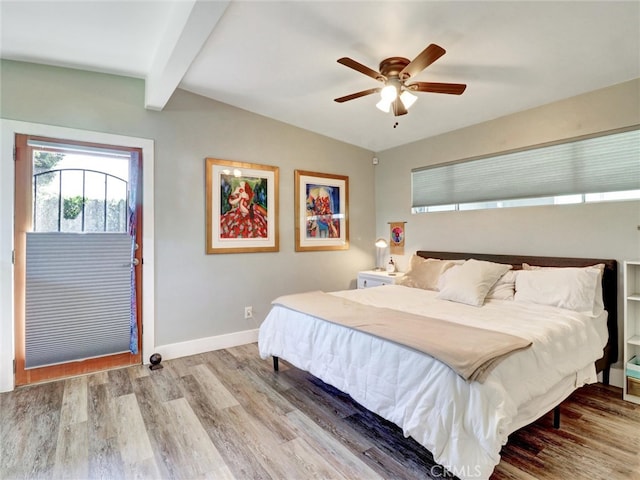 bedroom with baseboards, lofted ceiling with beams, ceiling fan, and wood finished floors