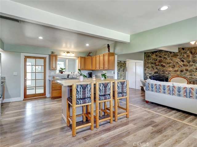 kitchen with light countertops, light wood-type flooring, beam ceiling, and a breakfast bar