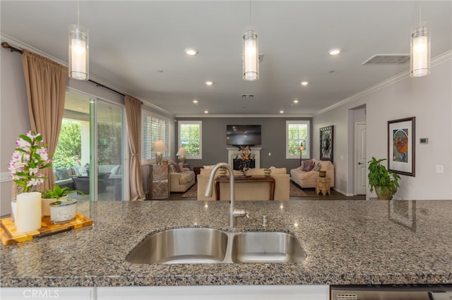 kitchen featuring crown molding, a sink, dark stone counters, open floor plan, and visible vents
