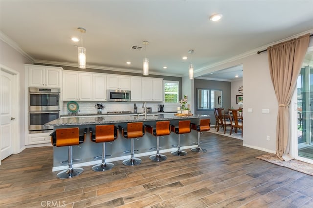 kitchen featuring a kitchen island with sink, visible vents, appliances with stainless steel finishes, dark stone countertops, and dark wood-type flooring