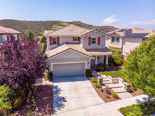 traditional home with concrete driveway, an attached garage, covered porch, and a mountain view