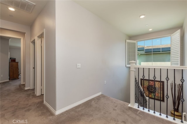 corridor featuring carpet floors, baseboards, an upstairs landing, and visible vents