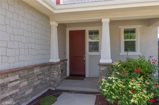 doorway to property featuring covered porch and stone siding