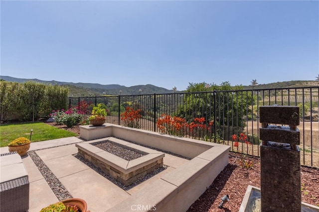 view of patio featuring fence, a fire pit, and a mountain view