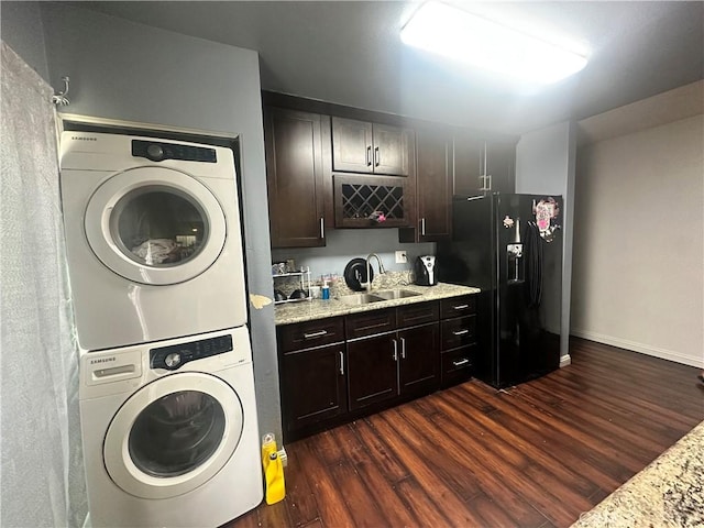 laundry room with laundry area, stacked washer and clothes dryer, indoor wet bar, dark wood-style floors, and a sink