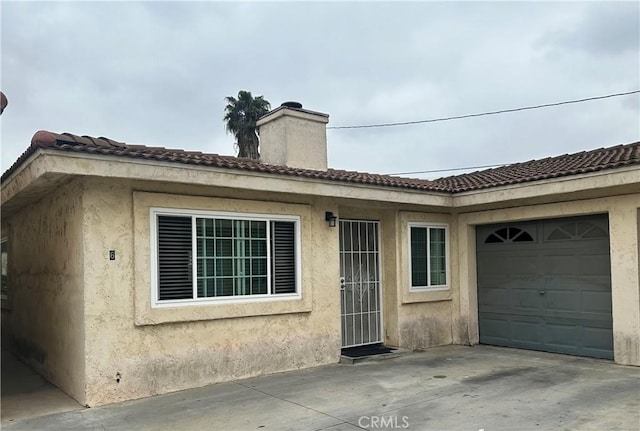 exterior space with stucco siding, a chimney, and a garage
