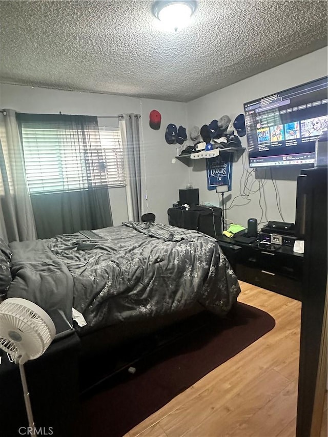bedroom with a textured ceiling and wood finished floors
