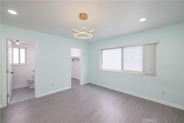 12246 Nadine Cir, Garden Grove, CA 92840 - unfurnished bedroom with wood finished floors, baseboards, connected bathroom, an inviting chandelier, and a spacious closet