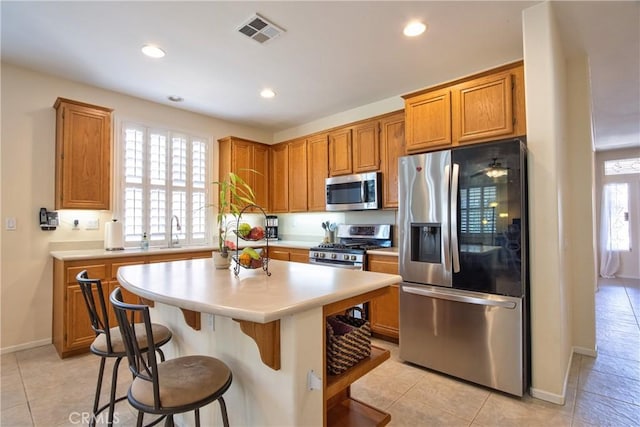 39312 Beringer Dr, Murrieta, CA 92563 - kitchen with appliances with stainless steel finishes, light countertops, a kitchen bar, recessed lighting, and a center island