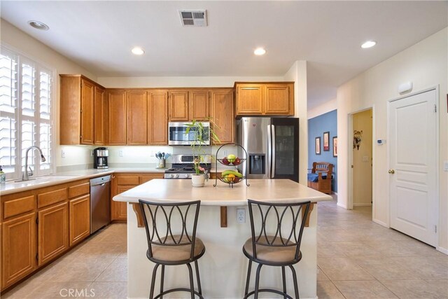 39312 Beringer Dr, Murrieta, CA 92563 - kitchen featuring appliances with stainless steel finishes, a sink, a kitchen island, light countertops, and a breakfast bar