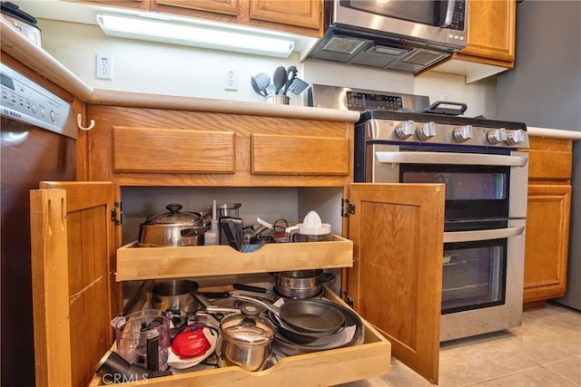 39312 Beringer Dr, Murrieta, CA 92563 - kitchen with stainless steel appliances, brown cabinetry, and light tile patterned flooring