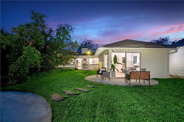 438 S Lamer St, Burbank, CA 91506 - back of house at dusk featuring an outdoor living space, a patio area, a lawn, and stucco siding