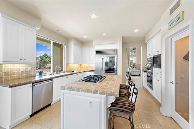 7 Rue Delacroix, Coto De Caza, CA 92679 - kitchen featuring stainless steel appliances, a sink, a kitchen island, white cabinets, and tasteful backsplash