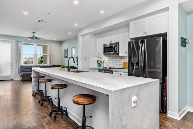 kitchen featuring visible vents, a breakfast bar, dark wood-type flooring, a sink, and stainless steel appliances