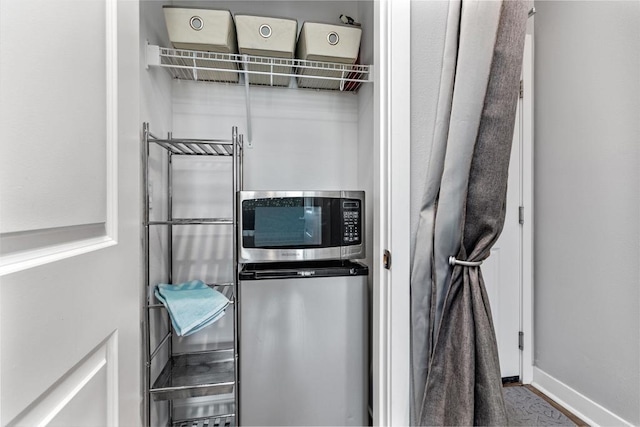 interior space featuring stainless steel microwave, baseboards, and refrigerator