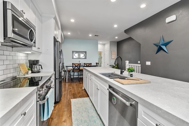 kitchen with decorative backsplash, appliances with stainless steel finishes, a sink, light countertops, and recessed lighting