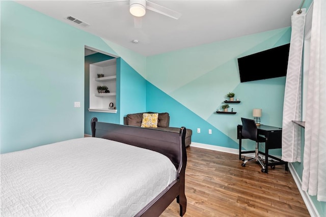 bedroom with baseboards, ceiling fan, wood finished floors, and visible vents
