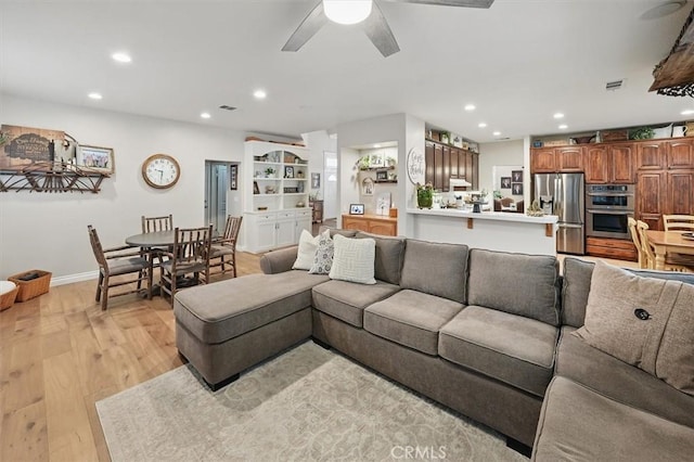 living area with light wood-type flooring, a ceiling fan, and recessed lighting