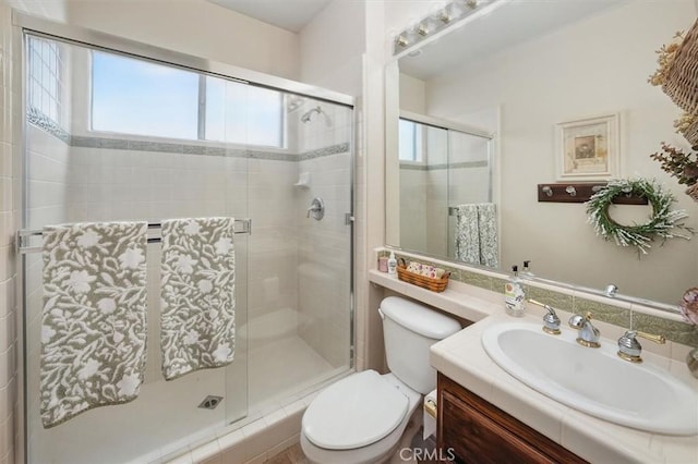 bathroom featuring vanity, toilet, and a stall shower