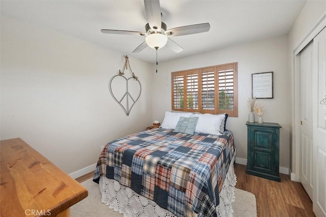 bedroom with ceiling fan, a closet, baseboards, and wood finished floors