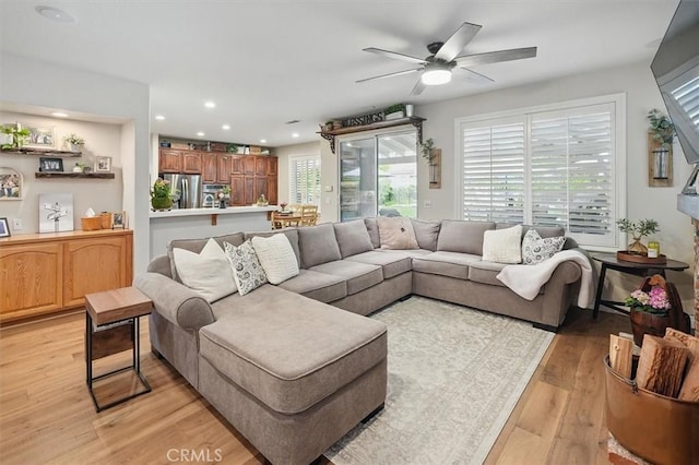 living room with light wood finished floors, a ceiling fan, and recessed lighting