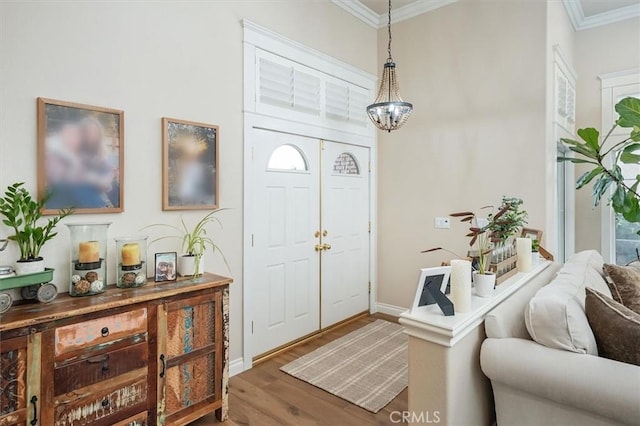 foyer entrance with crown molding, baseboards, an inviting chandelier, and wood finished floors