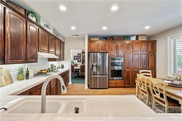 28433 Pinewood Ct, Saugus, CA 91390 - kitchen with appliances with stainless steel finishes, tile counters, under cabinet range hood, light wood-style floors, and recessed lighting