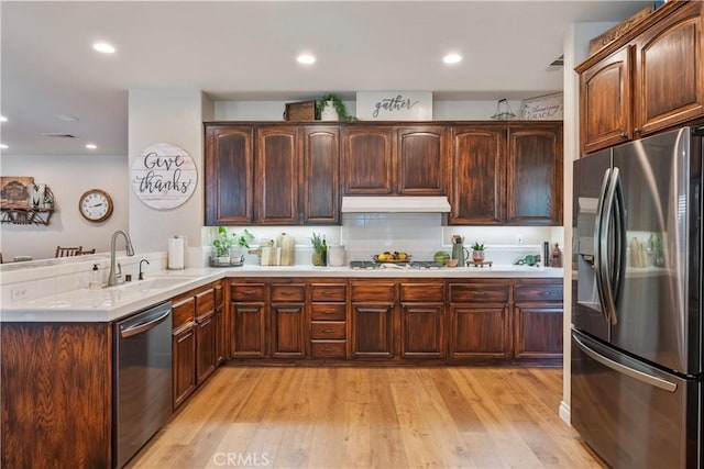 28433 Pinewood Ct, Saugus, CA 91390 - kitchen featuring stainless steel appliances, a peninsula, light countertops, under cabinet range hood, and light wood-style floors