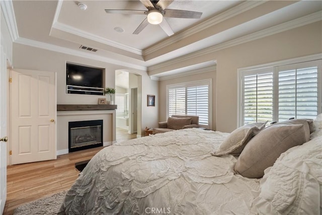 28433 Pinewood Ct, Saugus, CA 91390 - bedroom featuring a tray ceiling, a glass covered fireplace, light wood finished floors, arched walkways, and ornamental molding