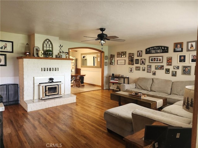 living room featuring ceiling fan, arched walkways, and wood finished floors
