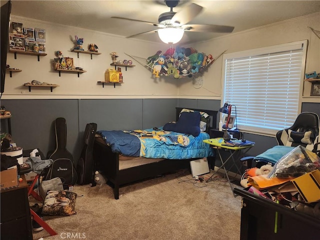 bedroom with a ceiling fan, crown molding, and carpet