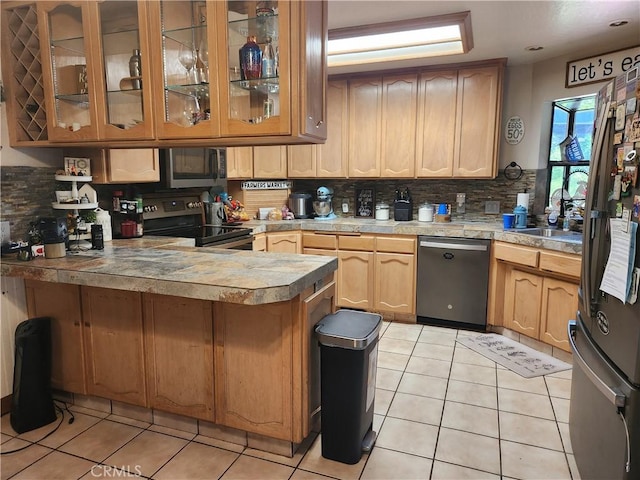 kitchen featuring a peninsula, appliances with stainless steel finishes, tasteful backsplash, and light tile patterned floors