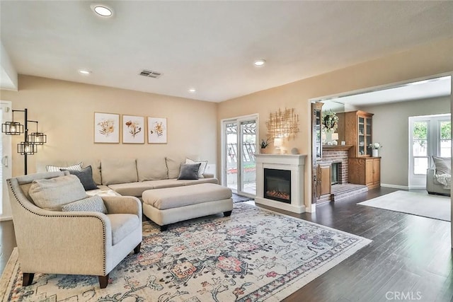 living room with visible vents, a glass covered fireplace, wood finished floors, baseboards, and recessed lighting