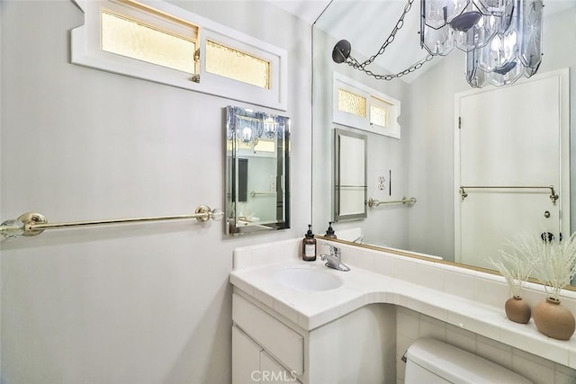 half bath featuring vanity, a chandelier, and toilet