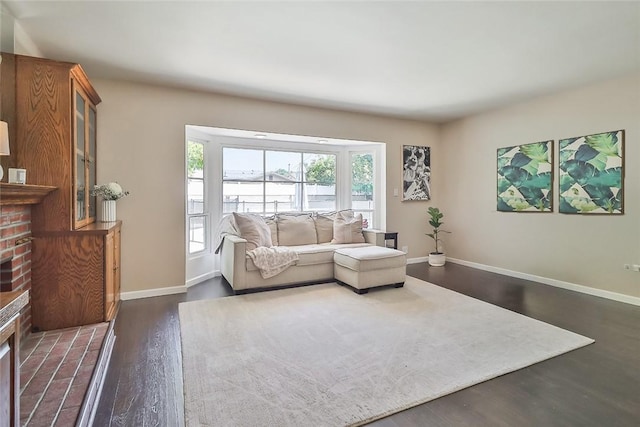 living room with baseboards, a brick fireplace, and dark wood-style flooring