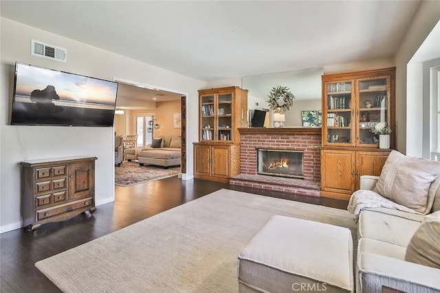 living room featuring visible vents, baseboards, wood finished floors, and a fireplace