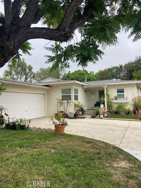 single story home with concrete driveway, an attached garage, stucco siding, and a front lawn